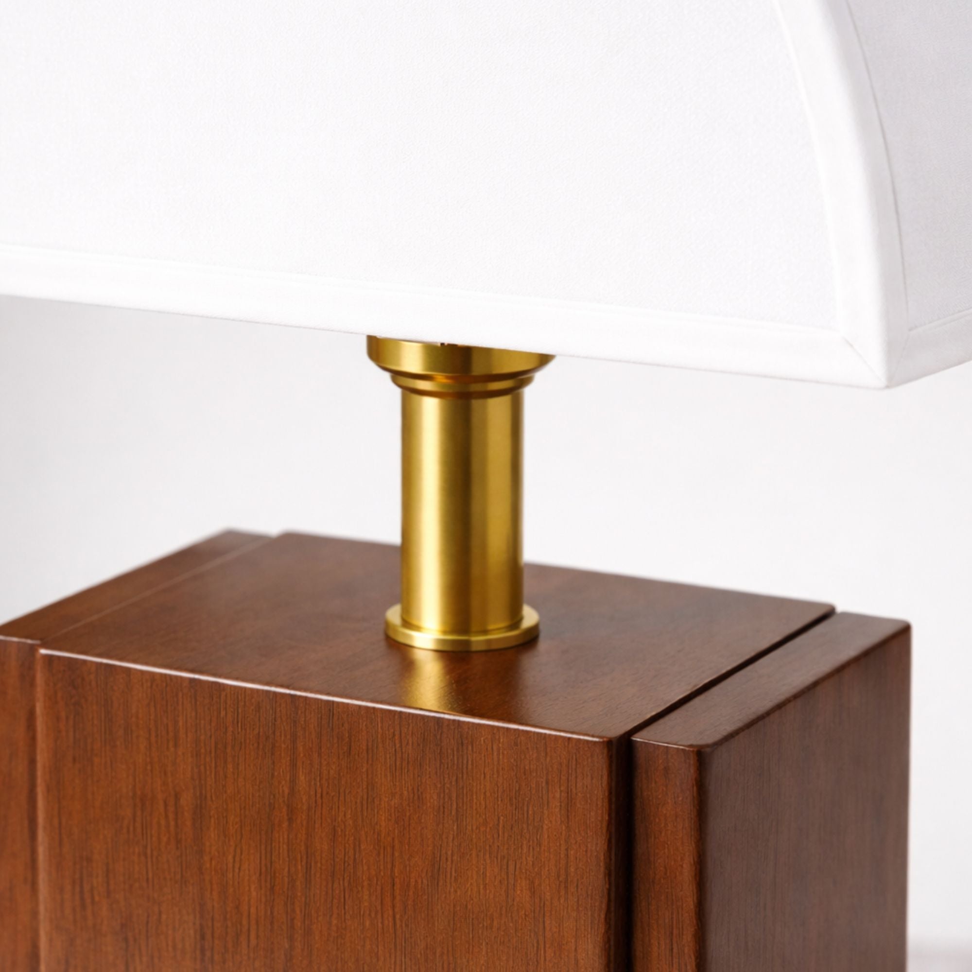 Närbild på bordslampa med vit skärm, guldfärgad detalj och träbas som visar material och finish i hög kvalitet