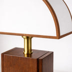 Närbild på bordslampa med vit skärm och träkant samt gulddetalj och träbas som visar material och exklusiv finish